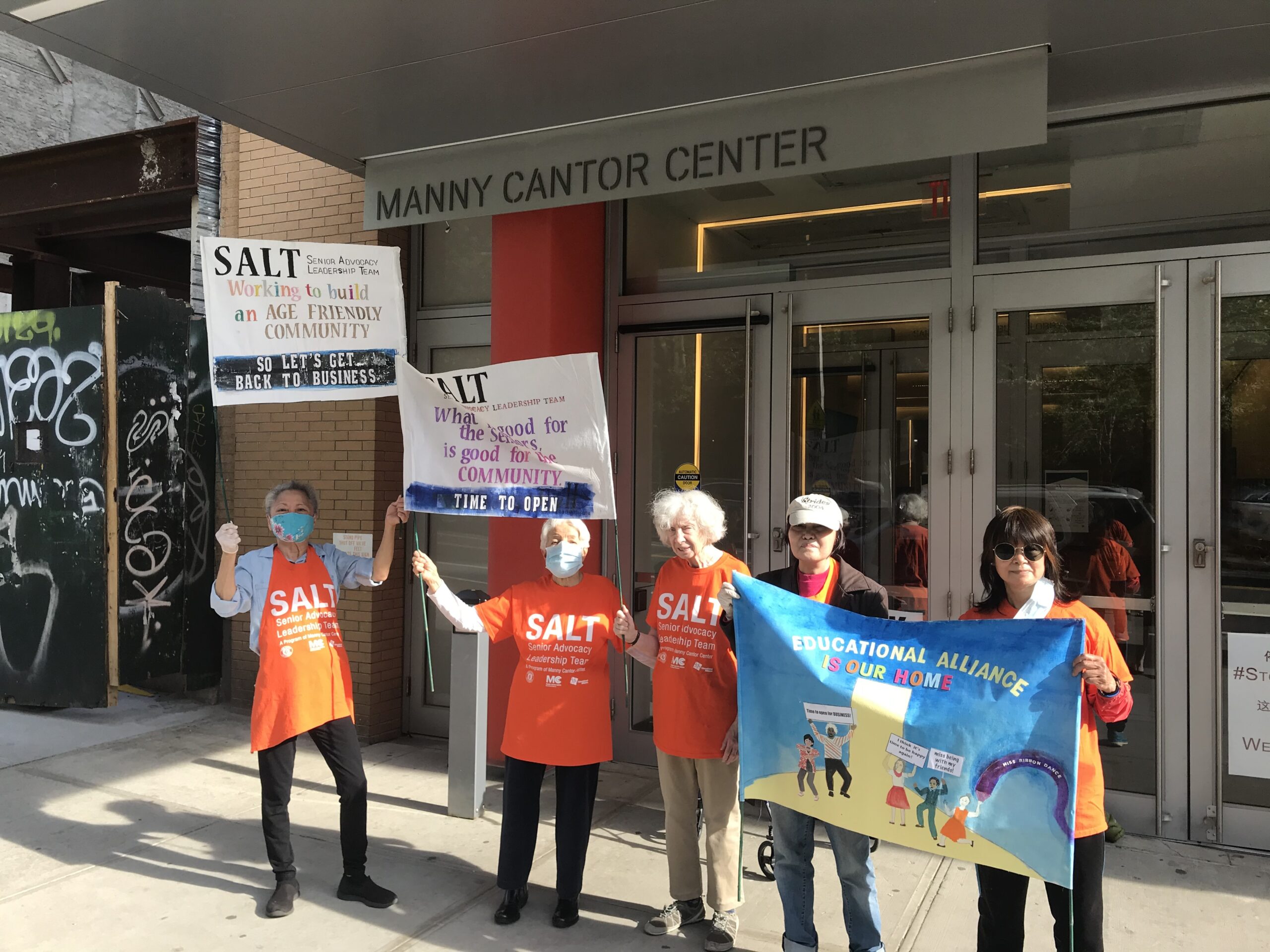 people with signs outside of the Manny Cantor Center